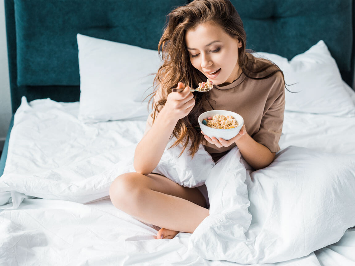 nő ágyban zabkásával - zabkása reggelire